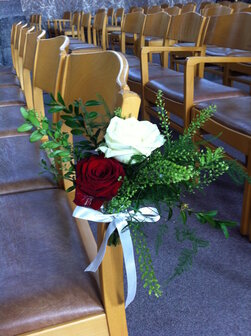 Stoeldecoratie kerk 1 rode en 1 witte roos met groensoorten